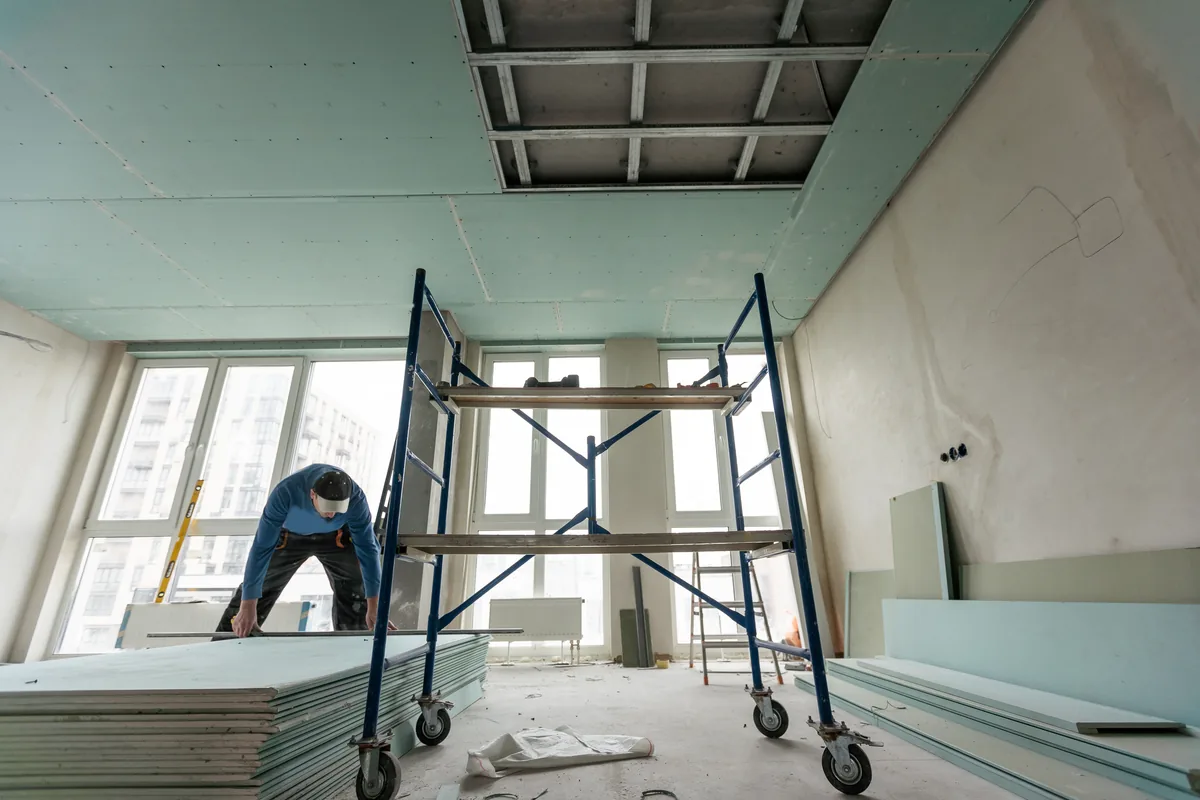 Worker installing a plasterboard ceiling